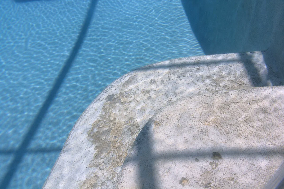 Chipped step edge and small delamination on an aging pool surface in Palm Bay